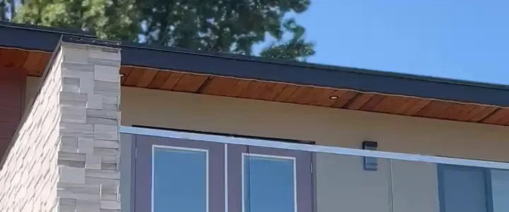 The same modern home by day, with the track tucked under the roofline
